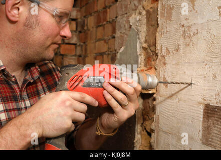 Richard Burr fore dans un mur pour sa colonne de bricolage. Banque D'Images