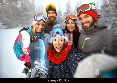 L'hiver, sport extrême et les gens concept - happy friends having fun sur la neige et en selfies Banque D'Images