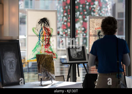 Un visiteur regarde la photographie et peintures exposées à 'une Journée de Guérison : à partir de la clinique afin de communauté," un événement honorant l'importance de l'art de guérir, au cours de mois de l'entretien au guerrier National Harbor à Oxon Hill, Maryland le 16 novembre 2017. (DoD Photo par Roger L. Wollenberg) Banque D'Images