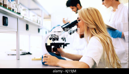 Groupe de scientifiques faisant des recherches à la microscope par Banque D'Images