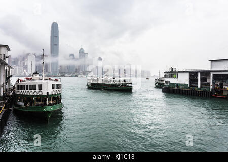 Star ferry sur un ciel nuageux avec la célèbre île de hong kong skyline de l'ensemble du port de Victoria dans le terminal Tsim Sha Tsui à Kowloon à Hong k Banque D'Images