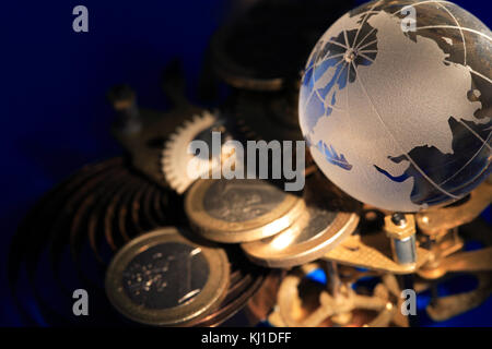 Globe en verre posé sur les pignons et de pièces sur fond bleu foncé Banque D'Images