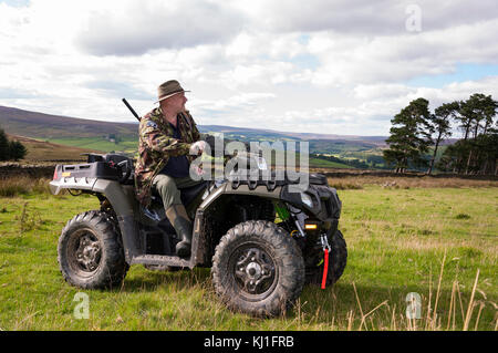 Un homme assis sur un quad (ATV) en train de tirer en faisant le contrôle vermin à Weardale dans le comté de Durham, dans le nord-est de l'Angleterre. Banque D'Images