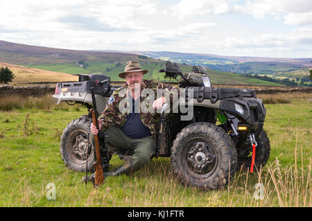 Un homme assis sur un quad (ATV) en train de tirer en faisant le contrôle vermin à Weardale dans le comté de Durham, dans le nord-est de l'Angleterre. Banque D'Images