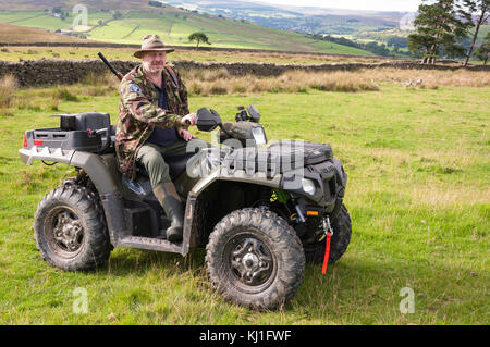Un homme assis sur un quad (ATV) en train de tirer en faisant le contrôle vermin à Weardale dans le comté de Durham, dans le nord-est de l'Angleterre. Banque D'Images