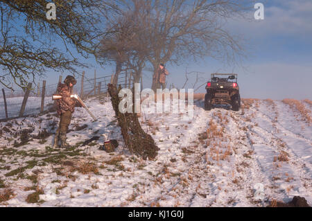 Un garçon et un homme sur un tir au pigeon d'hivers froid jour de décembre dans weardale dans le comté de Durham, d'une épaisse couche de neige au sol. Banque D'Images