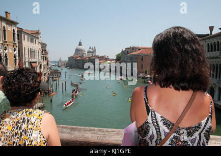 Deux femmes regardant des bateaux à rames et canoës sur le Grand Canal Venise Italie au cours de l'aviron de Volga Lunga festival le pont de l'Accademia Banque D'Images