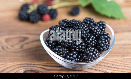 Les mûres juteux doux dans un bol en verre. Fruits frais de la forêt sur table en bois avec bramble floue) de la direction générale de l'arrière-plan. HD 16x9 ratio. Banque D'Images