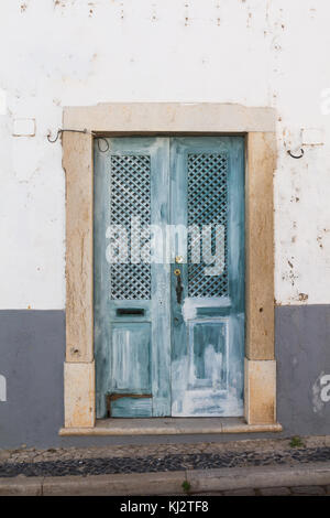 Texture en bois bleu porte dans un cadre en pierre. Mur Blanc de la chambre. Street à Faro, Portugal. Banque D'Images