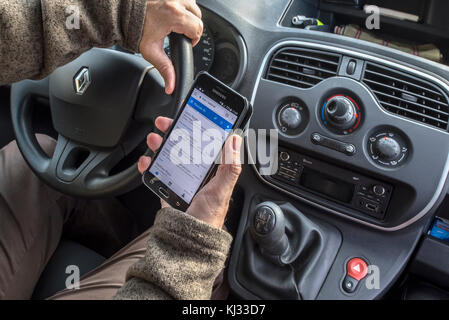 L'homme irresponsable au volant de la consultation des messages sur téléphone intelligent / smartphone / téléphone portable pendant la conduite automobile sur route Banque D'Images