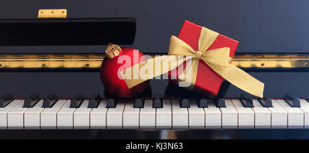 Balle rouge chritmas et boîte-cadeau avec archet d'or sur un clavier de piano classique, vue avant Banque D'Images