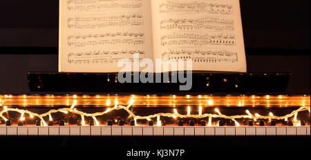 Lumières de Noël et scores sur un clavier de piano classique, vue avant Banque D'Images