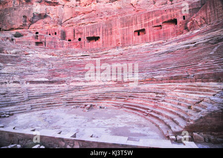 Amphithéâtre de l'époque romaine sculptée dans le grès rose à Pétra, en Jordanie. les façades de bâtiments creusés dans la roche derrière sont anciennes tombes. Banque D'Images