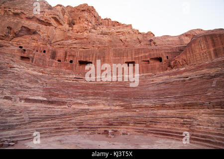 Amphithéâtre de l'époque romaine sculptée dans le grès rose à Pétra, en Jordanie. les façades de bâtiments creusés dans la roche derrière sont anciennes tombes. Banque D'Images