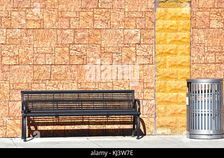 Un banc vide et corbeille en face de vieille brique. Banque D'Images