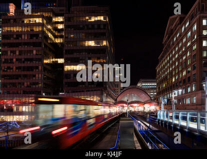 Canary Wharf de scène de nuit avec le Docklands light railway de système de transport en commun dans l'Est de Londres capturés comme des trains en mouvement Banque D'Images