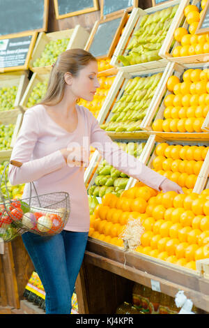 Dame choisissant oranges en magasin Banque D'Images