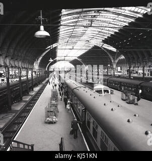 Années 1950, photo historique montrant la gare victorienne avec verrière à la gare de Paddington de Londres, avec des trains en attente d'embarquement des passagers sur les plates-formes, Praed Street, Londres, Angleterre, Royaume-Uni. Banque D'Images