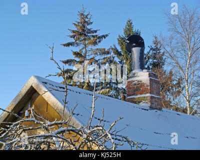 Maison de campagne vieille cheminée sur toiture est couverte de glace et brillant dans la lumière du soleil. Banque D'Images