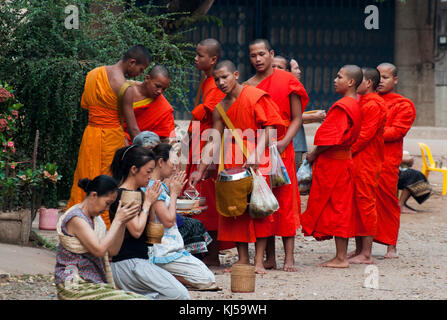 Les moines reçoivent l'aumône chaque matin les femmes de l'endroit, qui sont ainsi 'make mérite' pour eux-mêmes. Pakse, Laos Banque D'Images