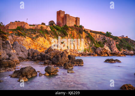 Talamone rock beach et forteresse médiévale rocca aldobrandesca murs et au coucher du soleil. maremma argentario destination touristique italien. toscane, italie. Banque D'Images