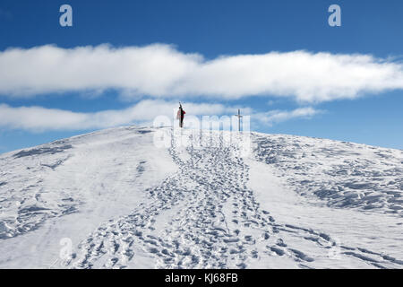 Avec skieur skis sur l'épaule aller jusqu'en haut de la montagne dans jolie journée soleil. Montagnes du Caucase en hiver, la Géorgie, la région, le Mont Gudauri. Kudebi Banque D'Images