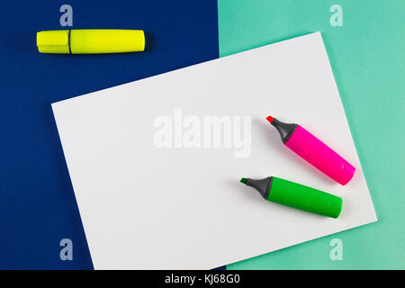 Jaune, rose et vert surligneurs marqueurs avec feuille de papier blanc sur fond coloré. Banque D'Images