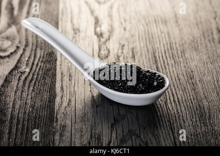 Dans une cuillère de caviar noir sur fond de bois Banque D'Images