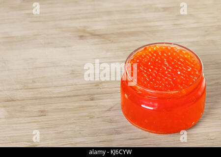 Caviar rouge dans un bocal de verre sur fond de bois Banque D'Images