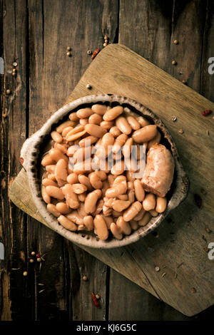 Capture d'un grand angle d'un bol en terre cuite avec un cassoulet de Castelnaudary, un ragoût de haricots typiques de l'Occitanie, en France, sur une table en bois rustique Banque D'Images