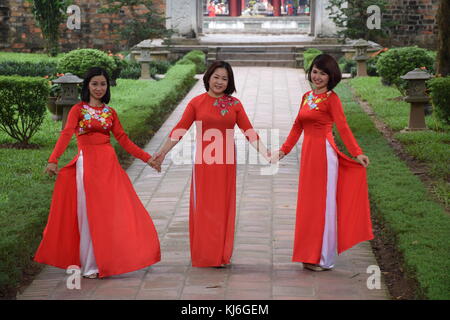 Trois belles femmes vietnamiens vêtus de rouge qui pose pour une séance photo à l'intérieur de temple de la littérature à Hanoi, Vietnam Banque D'Images