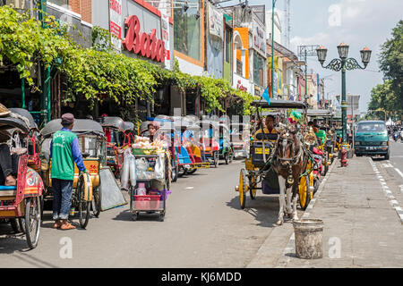 Vélos-pousse / becak et calèches pour les transports publics à Jalan Malioboro, principale rue commerçante à Yogyakarta, java, Indonésie Banque D'Images