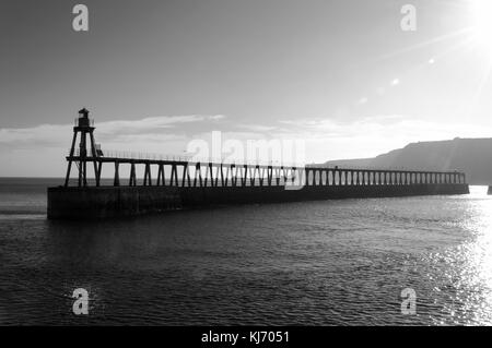 La jetée est à Whitby, dans le Yorkshire du nord, comme le soleil éclaire l'reflétant sur l'eau sur une journée en octobre. automnes Banque D'Images