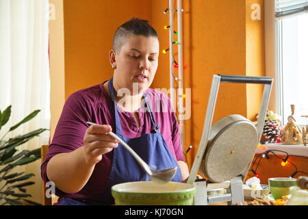 Jeune femme slovaque traditionnel gaufrettes de noël, servi avant le dîner de Noël. femme est assis dans la cuisine, derrière une table, avec subst Banque D'Images