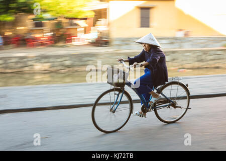 Personnes âgées de banlieue asiatique dans un chapeau conique à vélo dans les rues de la ville d'Hoi An Banque D'Images