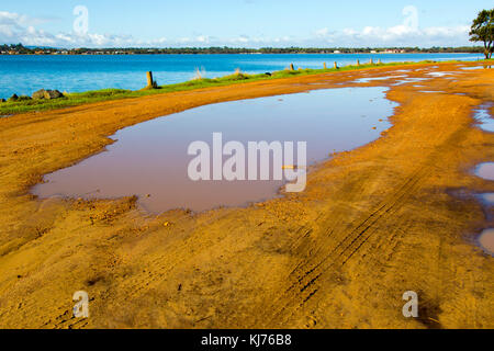 Flaques boueuses près des eaux calmes de l'estuaire de Leschenault Australind près de l'ouest de l'Australie après une douche de pluie sur un matin tôt en automne. Banque D'Images