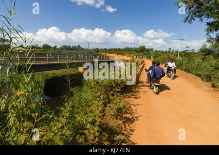 Boda boda motos taxis en voiture avec des passagers sur un chemin de terre près d'un pont en construction, Kenya, Afrique de l'Est Banque D'Images