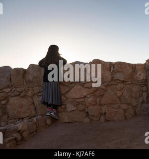 Vue arrière du girl leaning against wall au fort, Massada, désert de Judée, Région de la Mer Morte, Israël Banque D'Images