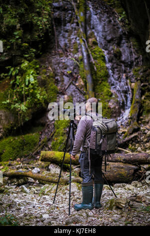 Photographe professionnel, avec des caméras de prise de vue sur trépied dans une rivière Banque D'Images