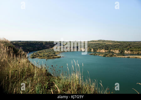 Paysage d'une ancienne carrière de granit industriel inondé rempli d'eau. Lac sur l'arrière-plan de roches et de sapins. Banque D'Images