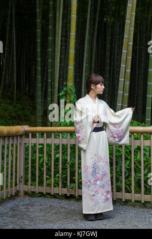 Jeune femme japonaise en kimono, en face d'une forêt de bambous à Kyoto, Japon Banque D'Images