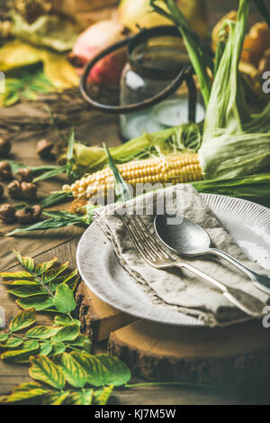 Table d'automne pour la célébration du jour de Thanksgiving. Assiette, couverts, porte-chandelle, l'automne des légumes de saison, fruits et feuilles jaunes sur ru Banque D'Images