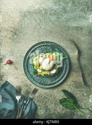 Le petit-déjeuner végétarien sain télévision à jeter. Farine de pain grillé avec de l'avocat, épinards et œufs pochés sur plaque sur fond de béton gris, vue du dessus, copiez s Banque D'Images