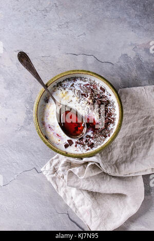 Bol de céréales au lait d'avoine avec des additifs confiture, chocolat, amandes et noix et baies, servi avec la cuillère sur gray table de cuisine. Vue de dessus avec l'espace Banque D'Images