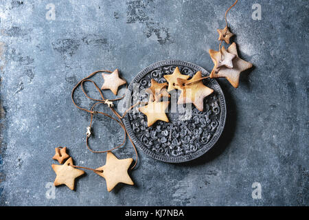 Sablés faits maison star shape sugar cookies autre taille avec du sucre en poudre sur le thread avec des bois sur la surface texture bleu. Tr de Noël Banque D'Images