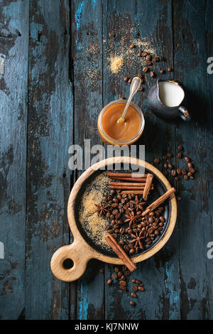 Pot de verre des spisy sauce caramel salé sur le service à bord avec des ingrédients sucre brun, grains de café, cannelle et crème cruche de ci-dessus. Plus de lo Banque D'Images