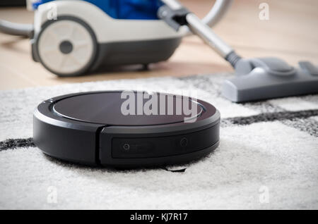 Aspirateur Robot travaille sur tapis. aspirateur traditionnel en arrière-plan Banque D'Images