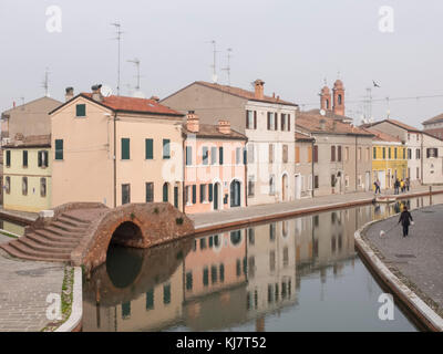 Comacchio, Fe, italie - 4 novembre 2017 : avis d'un des canaux traversant comacchio. La couleur des façades des maisons se reflètent sur l'eau. o Banque D'Images