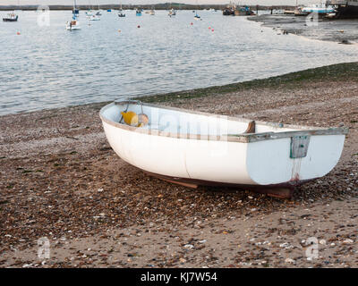 Petit bateau privé blanc garé amarrés sur beach front bay ; West Mersea, Essex, Angleterre, RU Banque D'Images