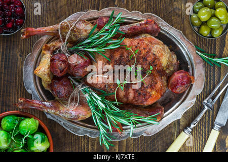 Canard festif avec les choux de Bruxelles, sauce aux canneberges et porcs dans la couverture sur table en bois - Vue de dessus Banque D'Images